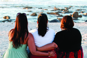 Three woman at the beach looking into the ocean