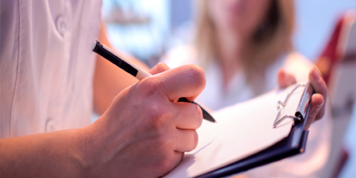 Close up of doctor writing on a medical chart.