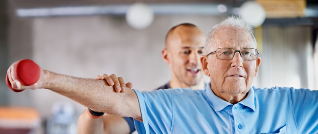 Physiotherapist helping a senior man with weights