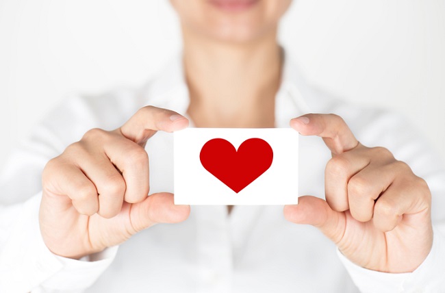 Person holding out a card with a red heart