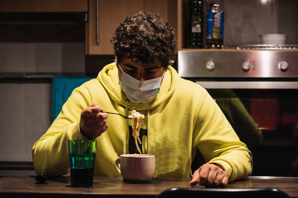 Young spanish man tries to eat wearing a mask