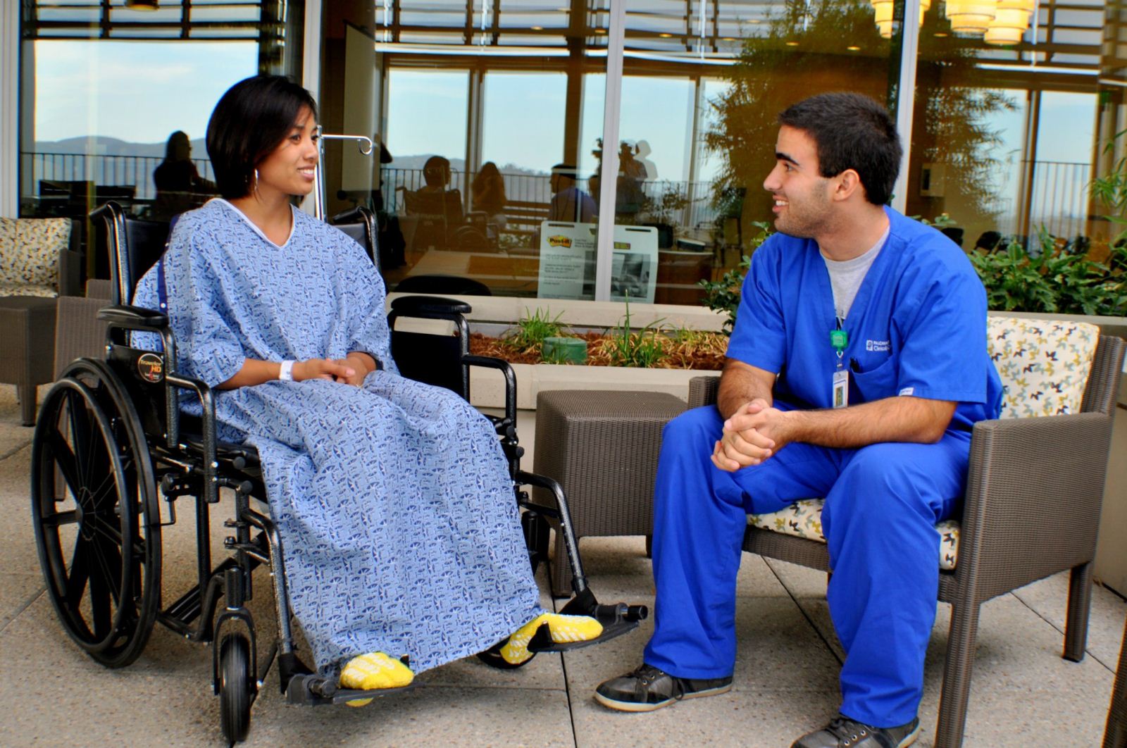 male nurse helping female patient in a wheel chair having a conversation