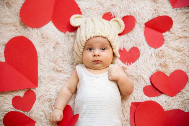 Baby on a rug with heart-shaped paper cutouts